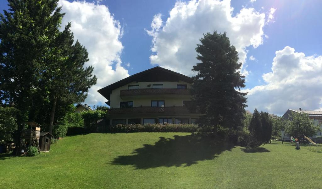 a large house on a green field with a tree at Haus Auer in Weyregg