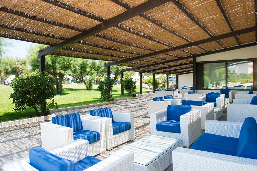 a patio area with chairs, tables and umbrellas at Hotel Del Levante in Torre Canne
