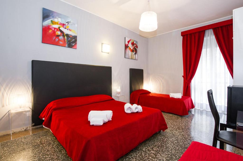 ローマにあるドムス ファビオラ ヴァティカーノのベッドルーム1室(ベッド2台、赤いシーツ、白いタオル付)