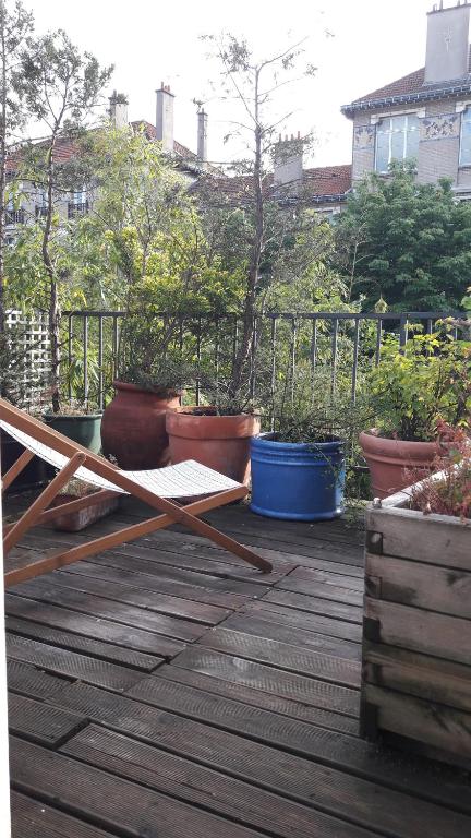 una terraza de madera con varias macetas. en Villa des iris, en París