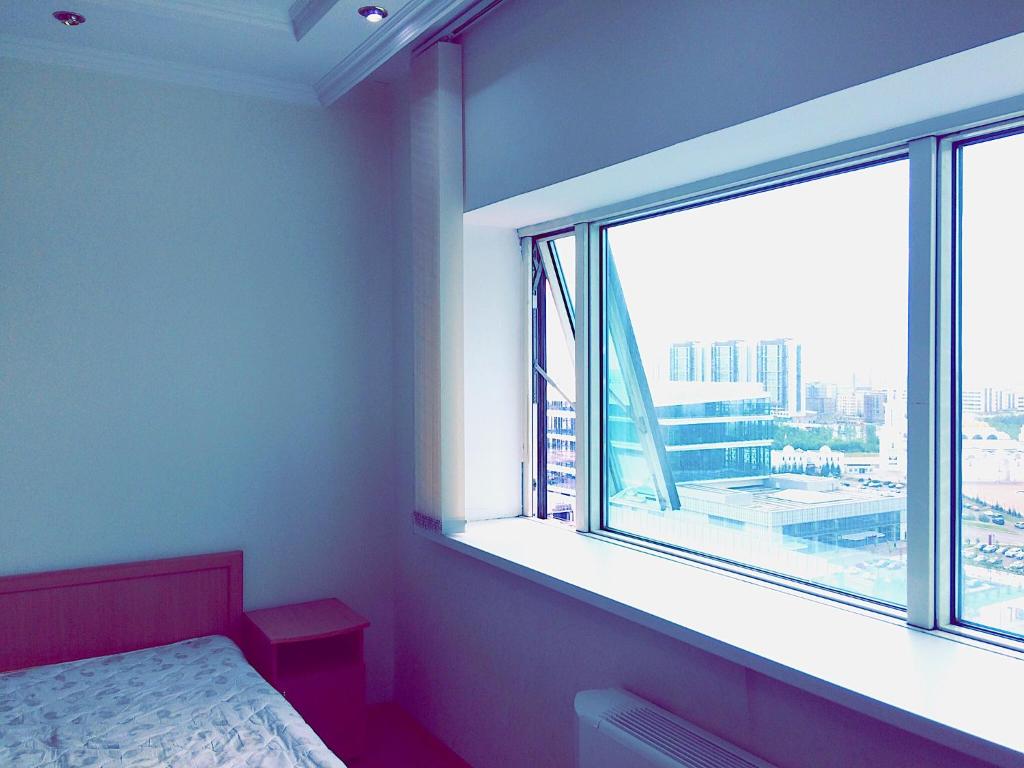 a bedroom with a large window with a view of a city at Amasing apartment on Dostyk 5 str in Astana