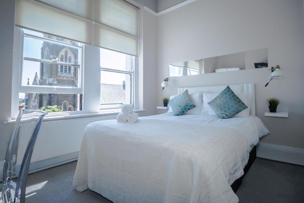 un dormitorio blanco con un osito de peluche sentado en una cama en The Mount Rooms, en Barry
