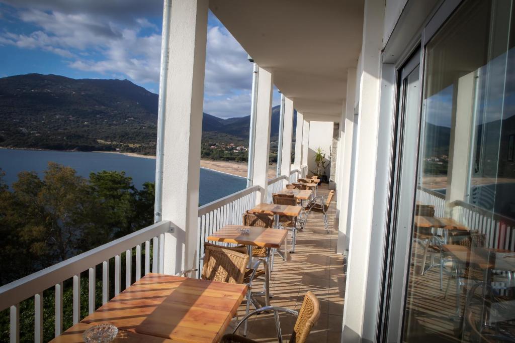 a balcony with tables and chairs and a view of a lake at Hotel Roc E Mare in Propriano