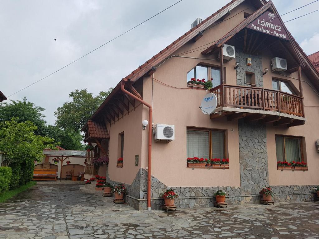 a building with a balcony and potted plants on it at Pensiunea Lőrincz *** Panzió in Sovata