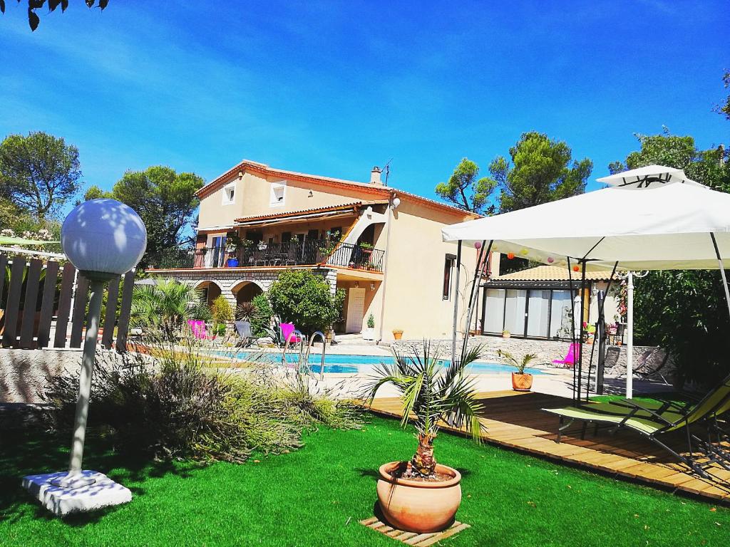 a house with a yard with a pool and an umbrella at Les Gites du Mas des Cigales in Nîmes