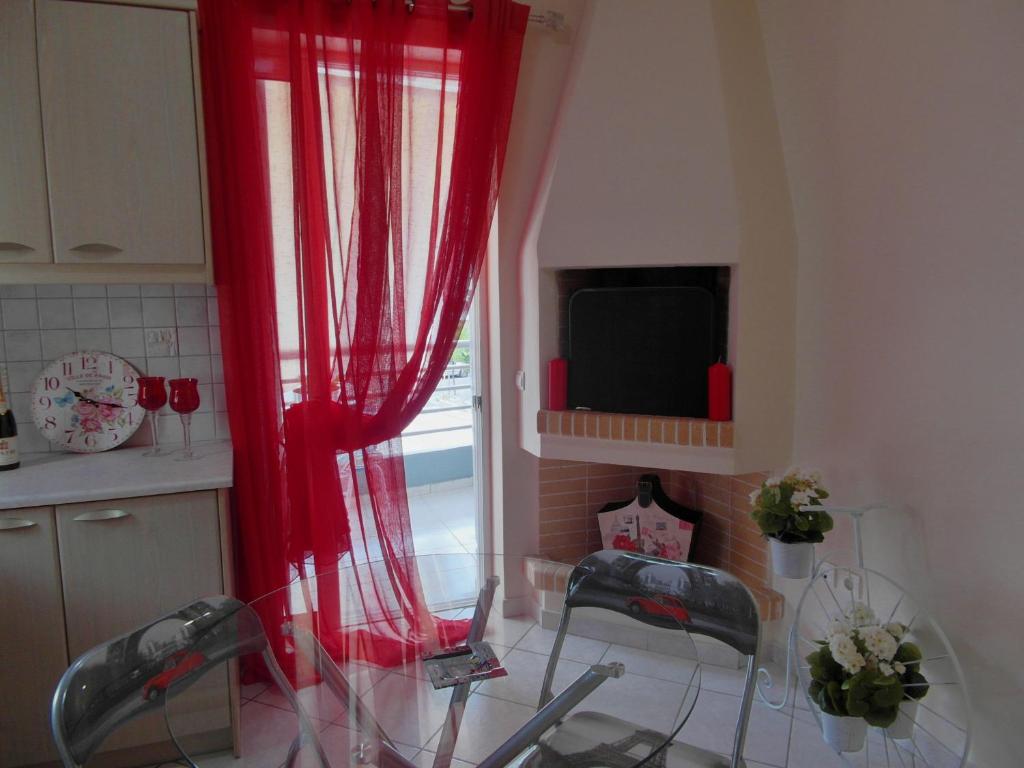 アテネにあるAthens Metro Mall Apartの赤いカーテン、ガラスのテーブルと椅子付きのキッチン