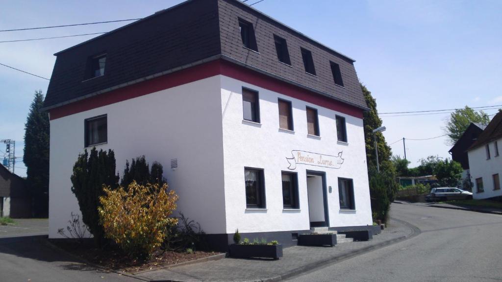 un bâtiment blanc et rouge avec un toit noir dans l'établissement Pension Lume, à Oberraden