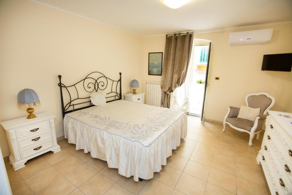 a white bedroom with a bed and a chair at Antica Dimora B&B Canosa in Canosa di Puglia
