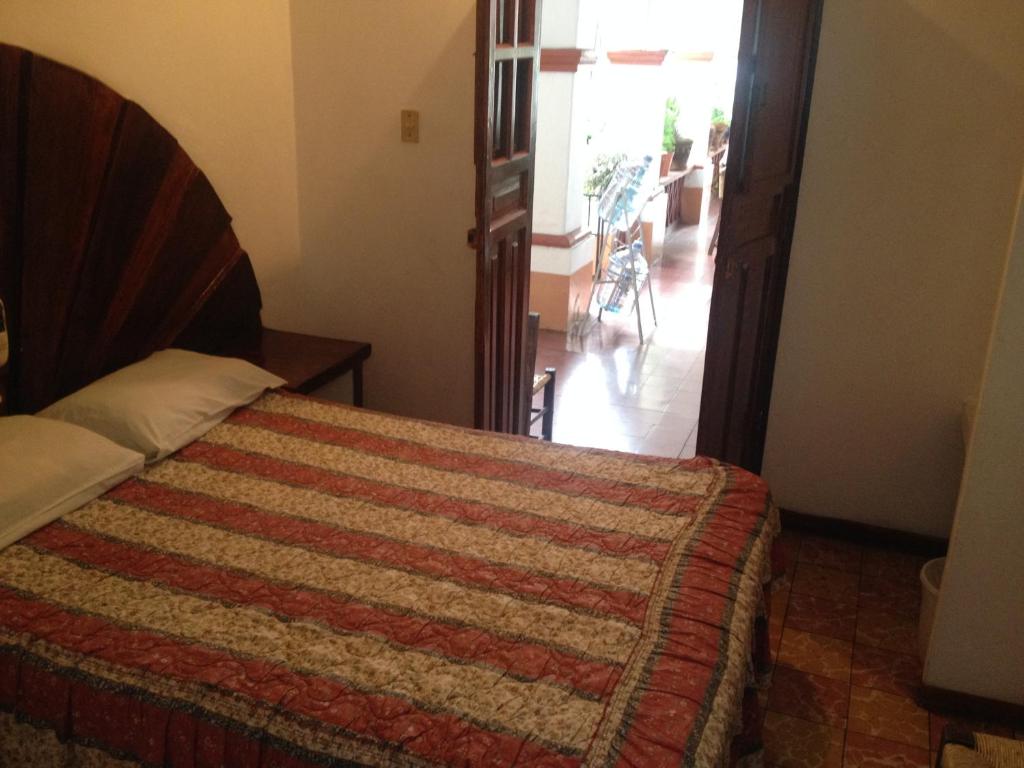a bedroom with a bed with a quilt on it at Hotel Posada Santa Anita in Taxco de Alarcón