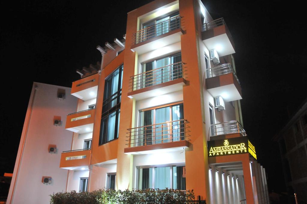 un edificio alto de color naranja con balcones por la noche en Apartments Ambassador en Ulcinj