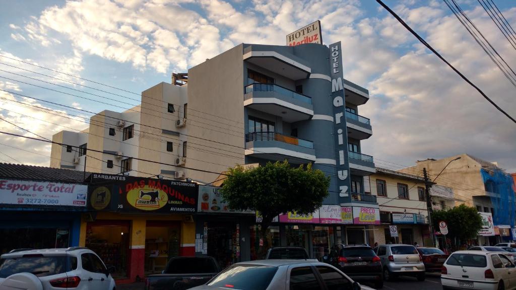 een gebouw in een stadsstraat met geparkeerde auto's bij Hotel Mariluz in Telêmaco Borba