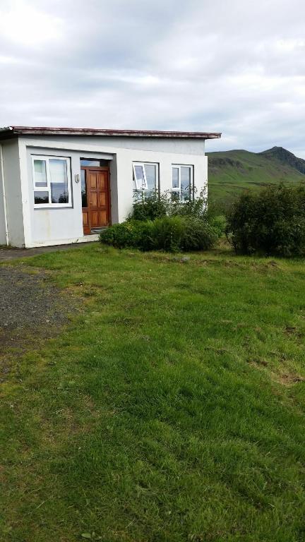 una pequeña casa blanca con un patio de césped en Giljur Guesthouse, en Vík