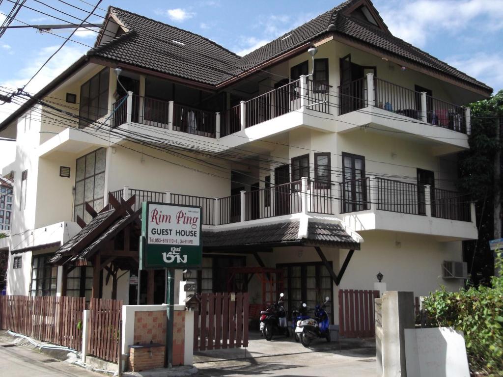 a large white building with a sign in front of it at Rim Ping Guest House in Chiang Mai