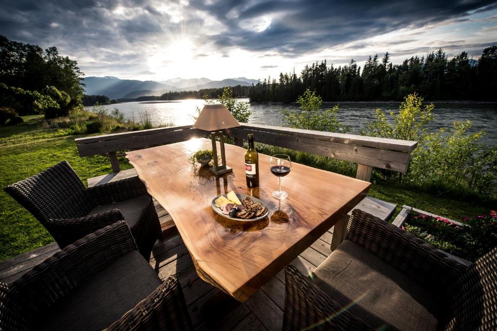 una mesa de madera con una botella de vino en la terraza en Skeena River House Bed & Breakfast, en Terrace
