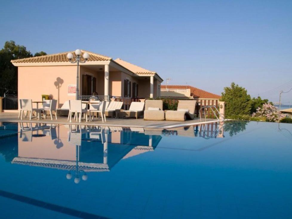 a villa with a swimming pool in front of a house at Melidron Hotel in Skala Kefalonias