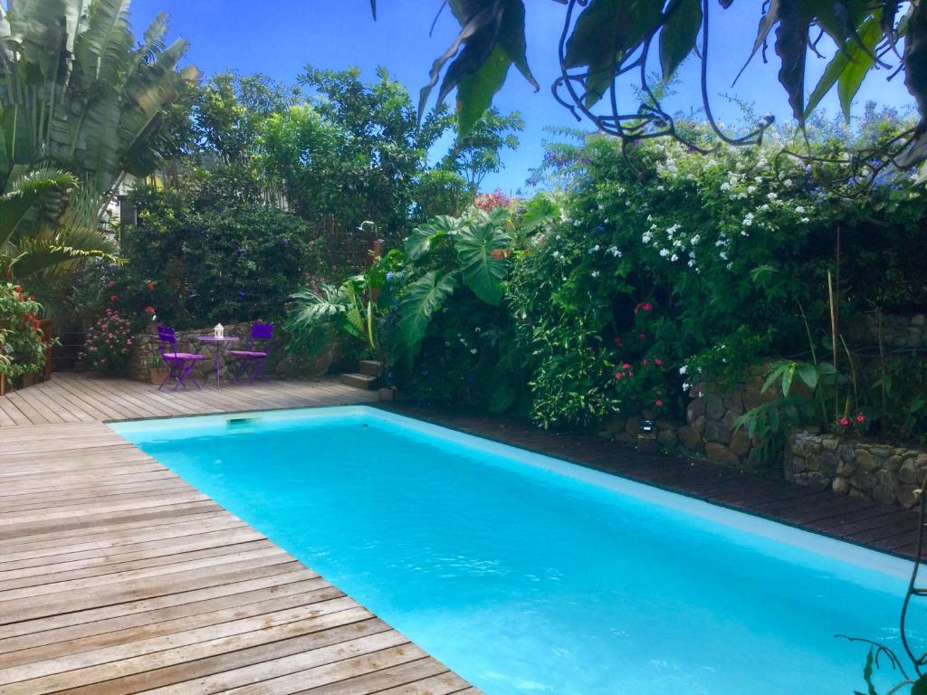 a swimming pool in a garden with a wooden deck at Fare Sunny in Punaauia