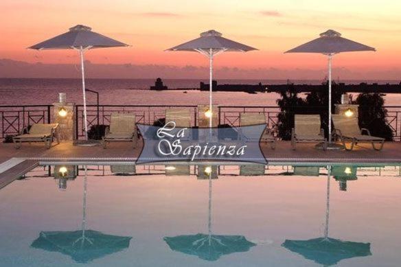 a swimming pool with umbrellas and the ocean at La Sapienza in Methoni