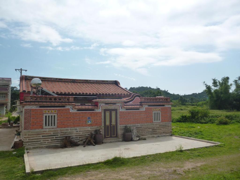 un petit bâtiment en briques avec deux chiens assis devant lui dans l'établissement Lieyu B&B, à Lieyu