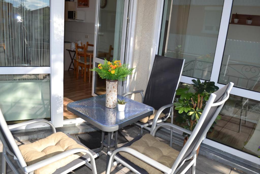 una mesa y sillas en un balcón con un jarrón de flores en Ludwig Apartment, en Ludwigsburg