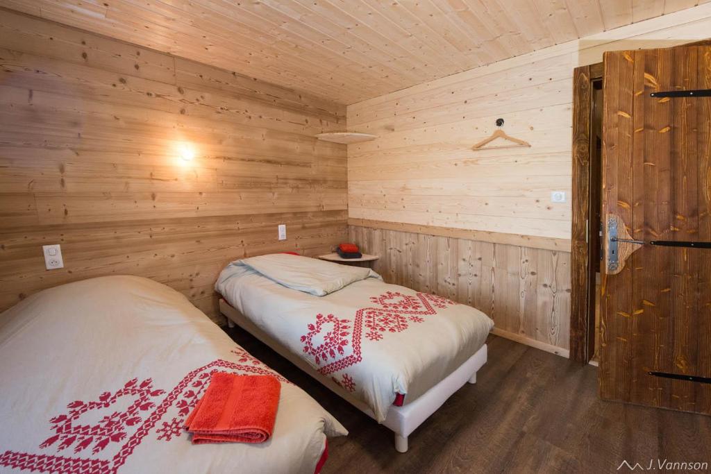 um quarto com 2 camas num chalé de madeira em chalet des cyclistes em La Bresse