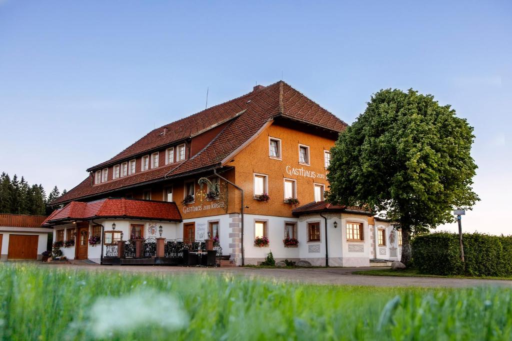 un gran edificio con un árbol delante en Gasthaus Zum Kreuz, en Sankt Märgen