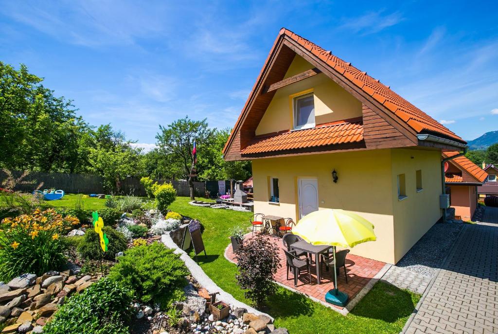 a small yellow house with an umbrella in a yard at Domceky Holiday in Liptovský Trnovec