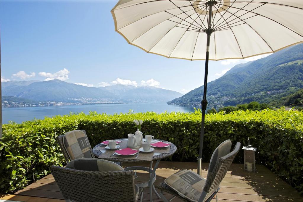 Pino Lago MaggioreにあるAppartamenti Vista da Sognoのパティオ(パラソル付きのテーブルと椅子付)