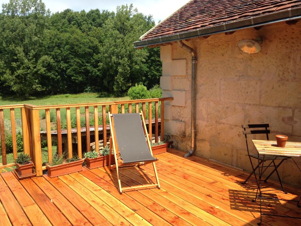 una terraza de madera con una mesa y una silla. en studio avec terrasse Abbaye d'Aiguevive, en Faverolles-sur-Cher