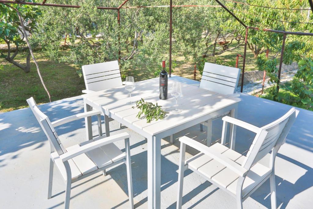 a white table with white chairs and a bottle of wine at Old SALONA in Solin