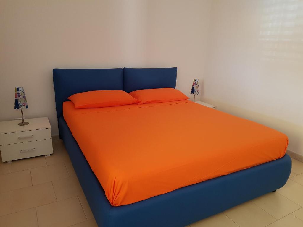 ein blaues Bett mit orangefarbener Bettwäsche und Kissen in einem Zimmer in der Unterkunft Residenza Carone in Porto Cesareo