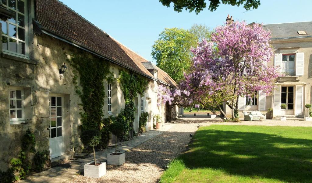 an old building with a tree with purple flowers at Le Grand Saint-Marc in Vendôme