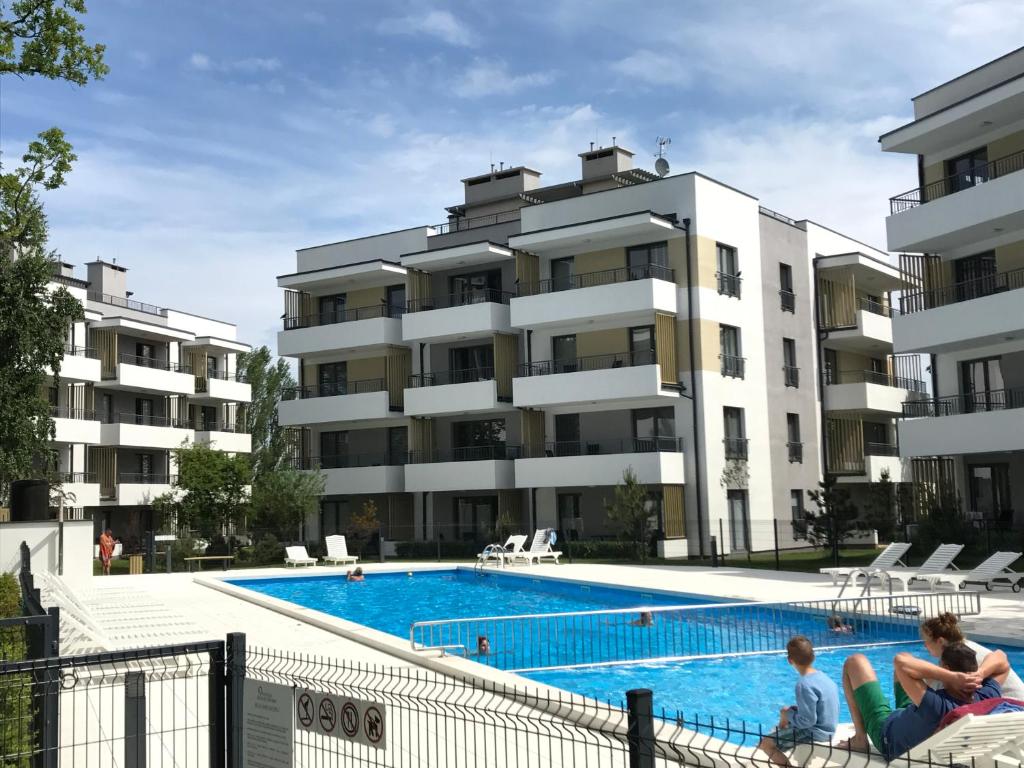 two people sitting in front of a large apartment building at Rezydencja Ustronie Morskie Zachodnia in Ustronie Morskie