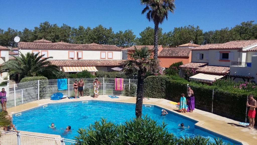 a group of people standing around a swimming pool at Les Andalouses in Cap d'Agde