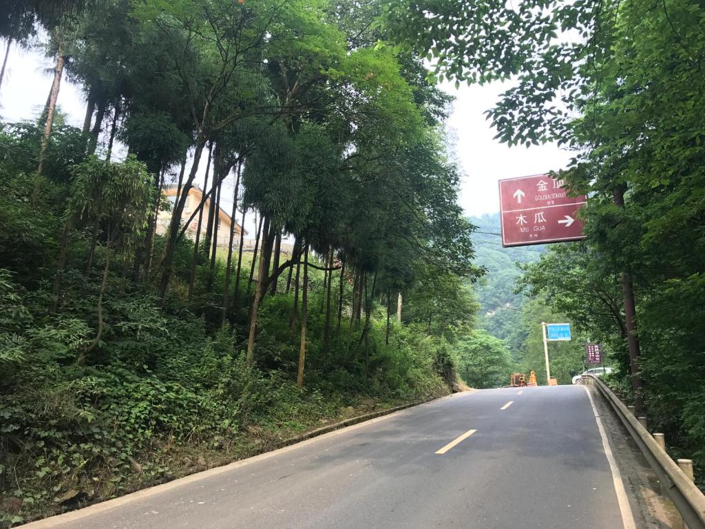 un camino vacío con árboles a un lado de la carretera en Mount Emei Feng Lin Yue Hotel, en Emeishan