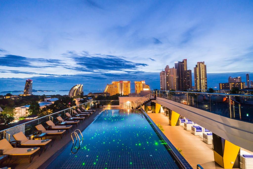 a rooftop pool with lounge chairs and a city skyline at Blue Boat Design Hotel in North Pattaya