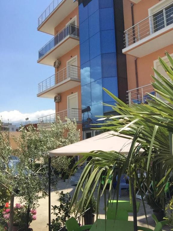 a building with a white umbrella and some plants at Bello Apartaments in Orikum