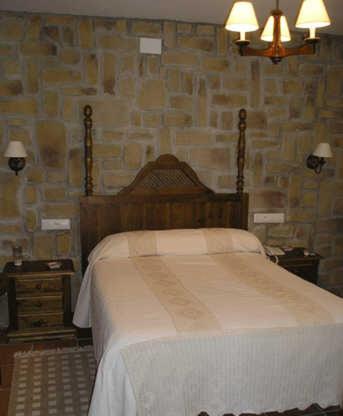 a bedroom with a bed and a stone wall at El Perro de Paterna in Paterna de Rivera