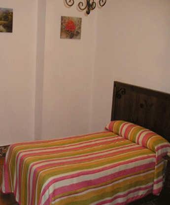 a bed with a colorful blanket on it in a room at El Perro de Paterna in Paterna de Rivera