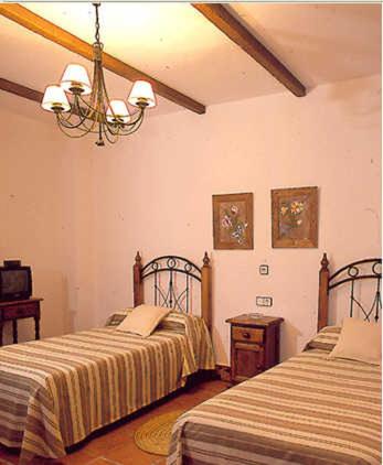a bedroom with two beds and a chandelier at El Perro de Paterna in Paterna de Rivera