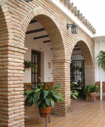 a brick archway with two potted plants on a patio at El Perro de Paterna in Paterna de Rivera