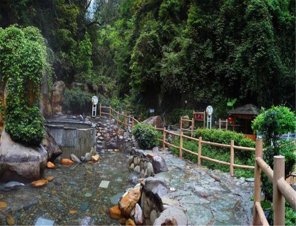 un giardino con rocce, recinzione e cascata di Longsheng Hot Spring Resort a Longsheng