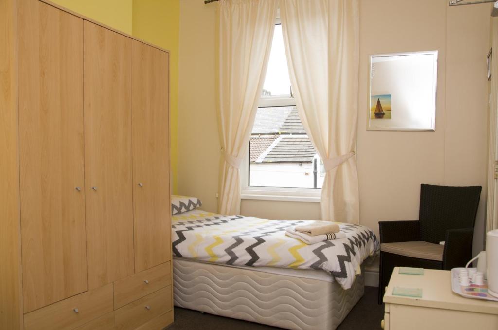 a small bedroom with a bed and a window at Pretoria Guest House in Bridlington