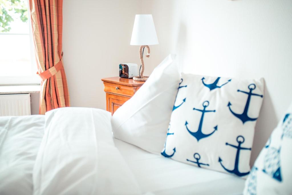a bedroom with a bed with blue and white pillows at Strandhotel Strande in Strande