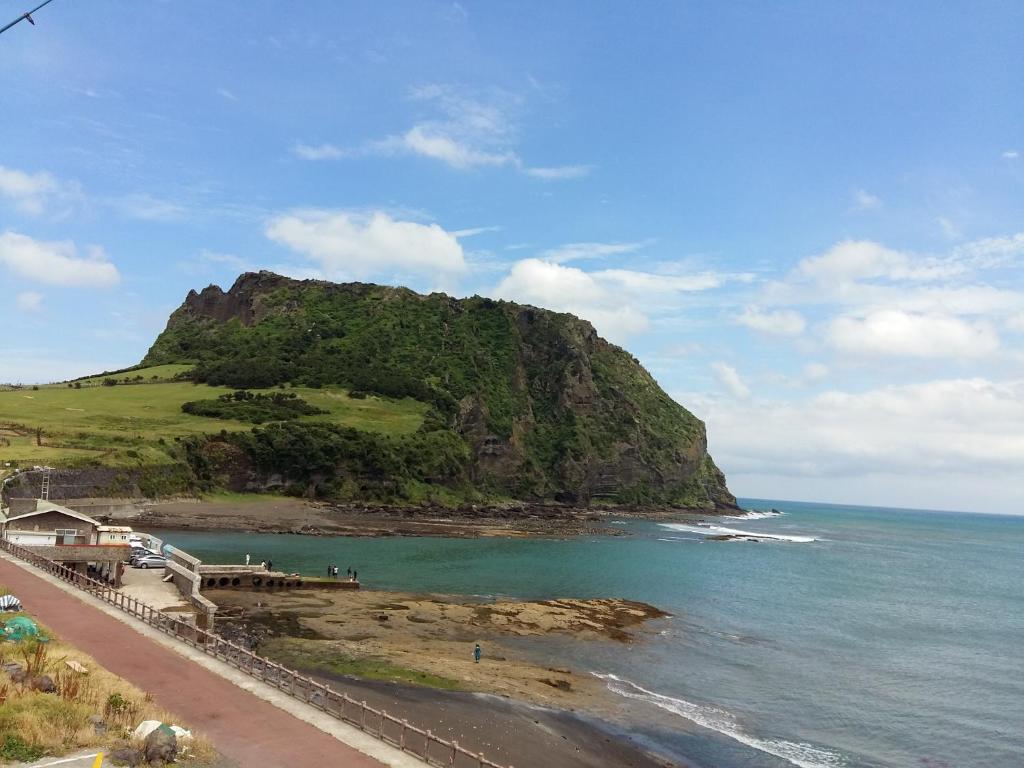 een uitzicht op een strand met een berg bij Nice View Guesthouse in Seogwipo