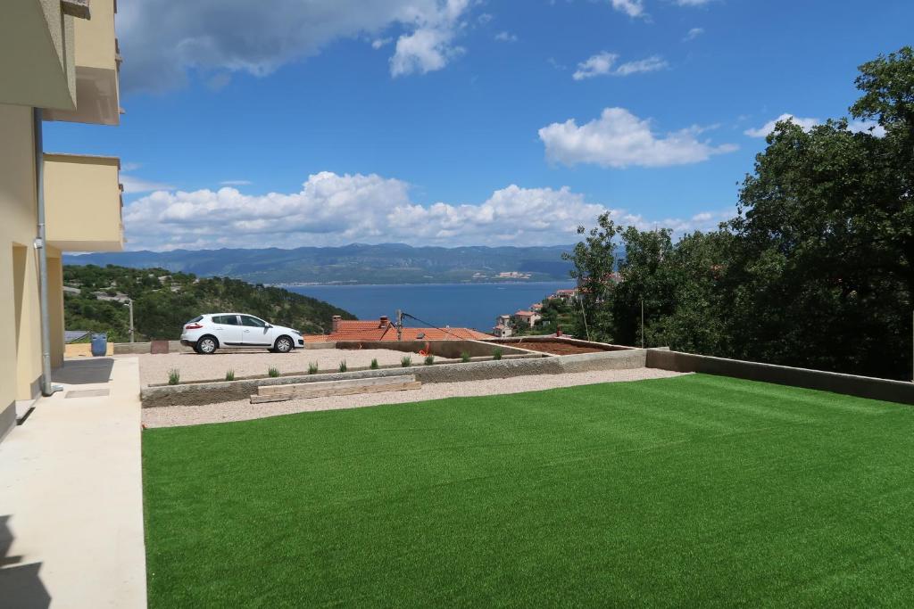 a green lawn on the side of a house at Apartmani Marin in Vrbnik