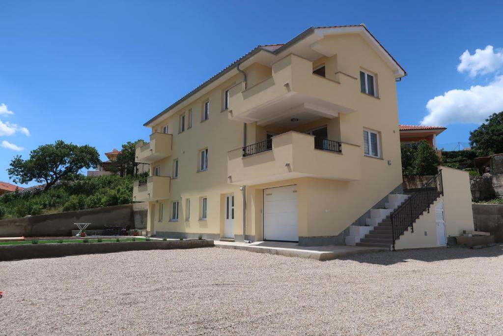 a large yellow building with a garage at Apartmani Marin in Vrbnik
