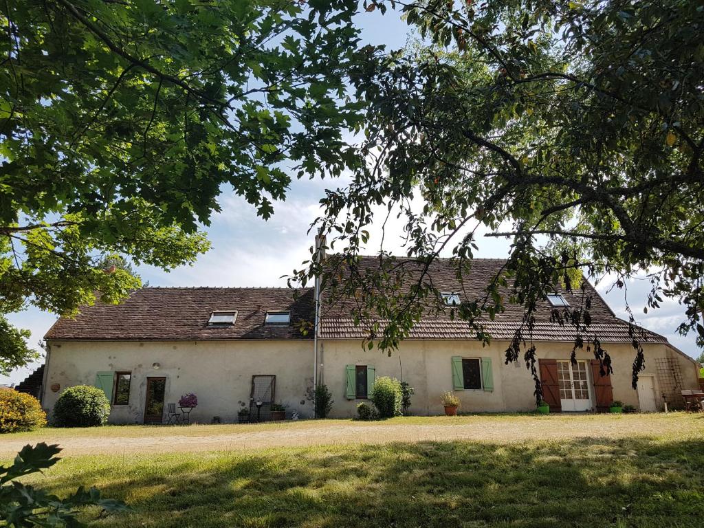 Casa blanca grande con árboles y ventanas verdes en Chambres d'hotes le Matou Roux, en Isle-et-Bardais