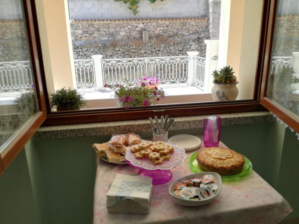 una mesa con un plato de comida delante de una ventana en B&B Fiori, en Bonorva