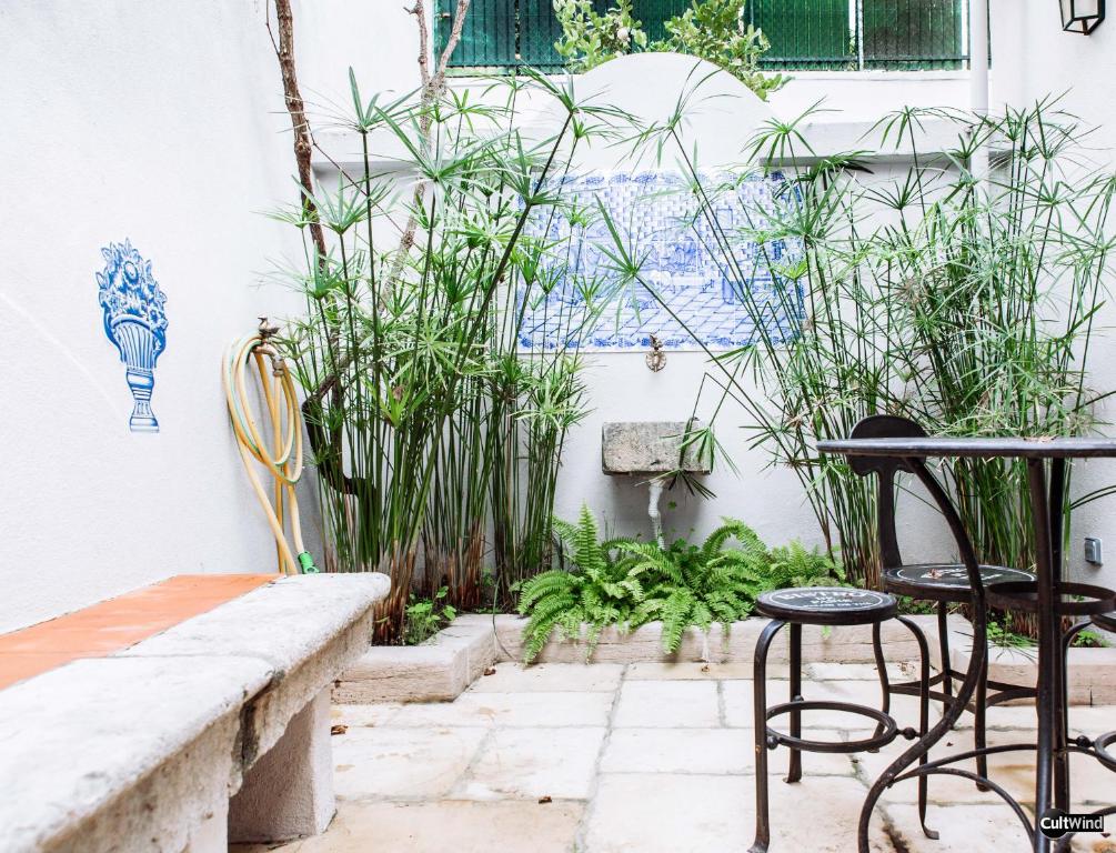 a patio with chairs and a table and plants at Villa Marquês near Tejo River in Cruz Quebrada