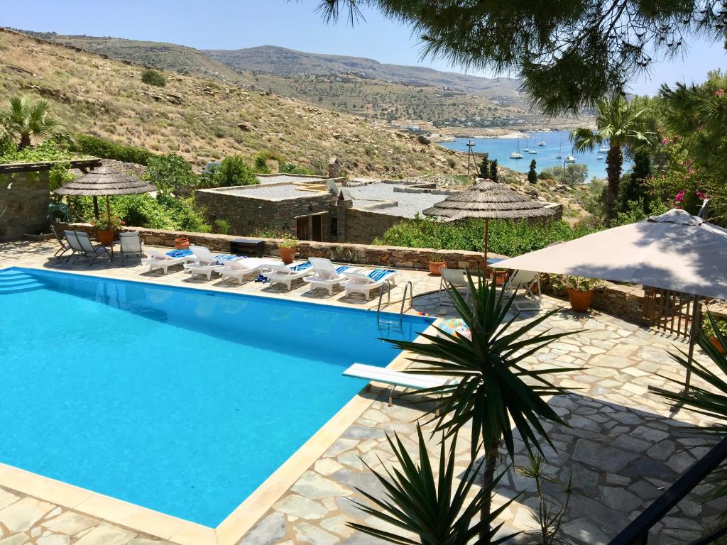 een zwembad met stoelen en parasols naast een resort bij Villa Tereza, 3-Min Walk to Koundouros Beach Waves in Koundouros